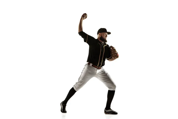 Honkbal speler, werpster in een zwart uniform aan het oefenen op een witte achtergrond. — Stockfoto