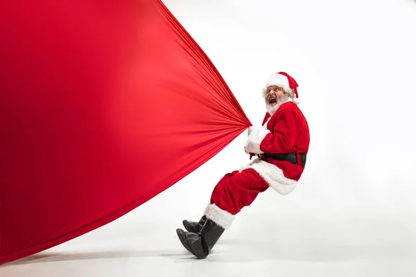 Santa Claus tirando de la bolsa enorme llena de regalos de Navidad aislado sobre fondo blanco — Foto de Stock