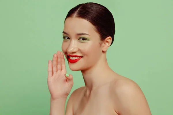 Portrét krásné mladé ženy s jasným make-up izolované na zeleném pozadí studia — Stock fotografie
