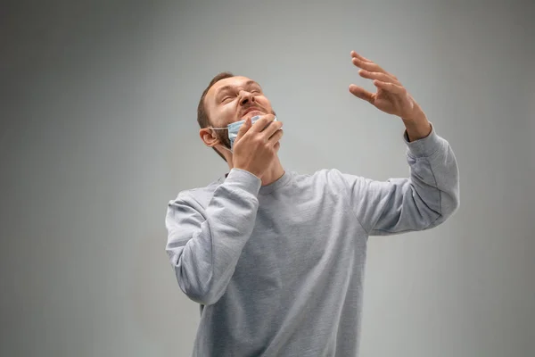Λευκός άνδρας με μάσκα προστασίας του αναπνευστικού από την ατμοσφαιρική ρύπανση και σούρουπο σε γκρι φόντο στούντιο — Φωτογραφία Αρχείου