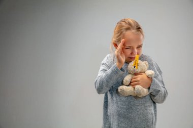 Solunum koruyucu iğne tokası takan beyaz bir kız hava kirliliğine karşı ve gri stüdyo arka planında alacakaranlığa karşı