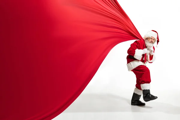 Noel Baba, Noel hediyeleriyle dolu koca çantayı çekiyor. Beyaz arka planda izole edilmiş. — Stok fotoğraf