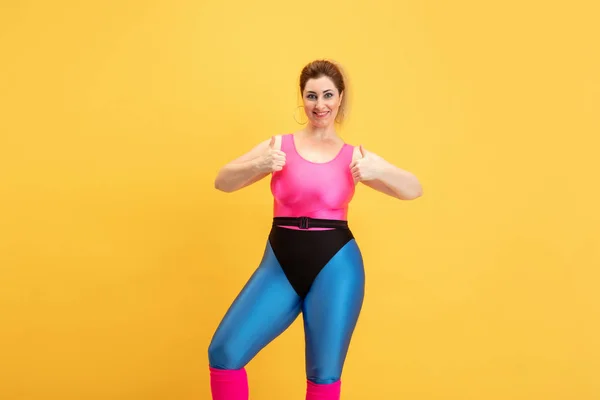 Young caucasian plus size female models training on yellow background — Stock Photo, Image