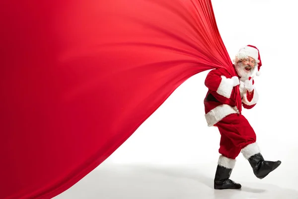 Noel Baba, Noel hediyeleriyle dolu koca çantayı çekiyor. Beyaz arka planda izole edilmiş. — Stok fotoğraf