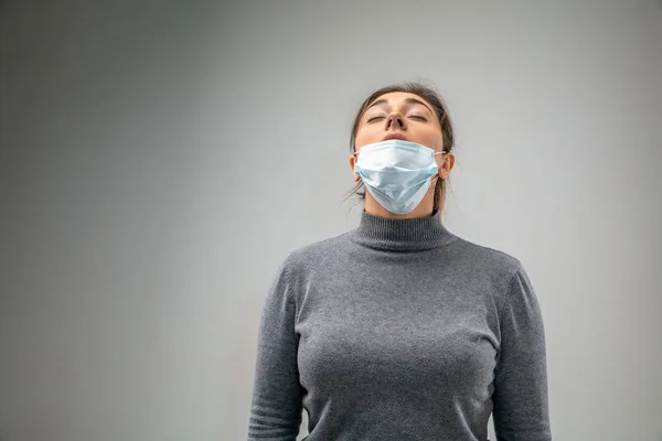Kaukázusi nő visel légúti védelem maszk légszennyezés ellen, és alkonyat szürke stúdió háttér — Stock Fotó