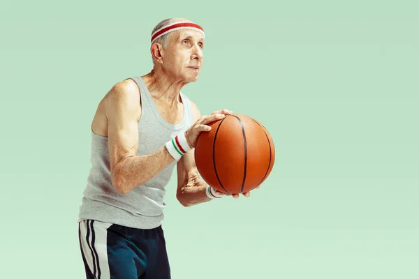 Homme âgé jouant au basket-ball dans des vêtements de sport isolés sur fond vert — Photo