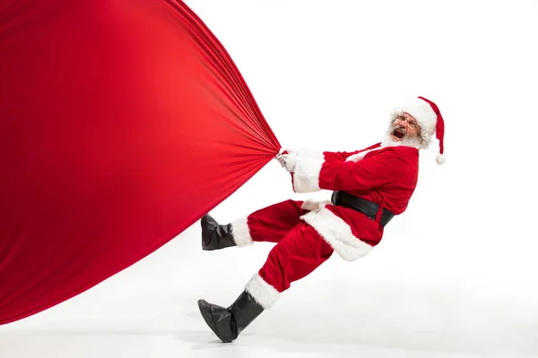 Santa Claus tirando de la bolsa enorme llena de regalos de Navidad aislado sobre fondo blanco — Foto de Stock