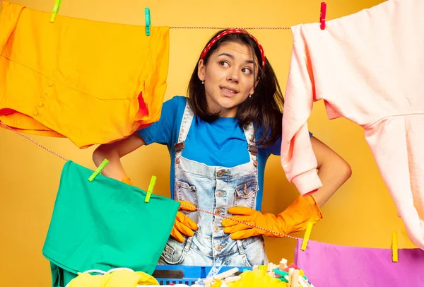 Engraçado e bela dona de casa fazendo tarefas domésticas no fundo amarelo — Fotografia de Stock