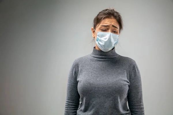 Mujer caucásica que usa la máscara de protección respiratoria contra la contaminación del aire y el atardecer en el fondo gris del estudio — Foto de Stock