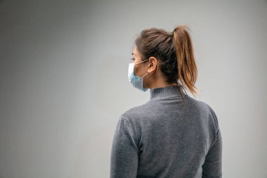 Solunum maskesi takan beyaz kadın hava kirliliğine karşı ve gri stüdyo arka planında alacakaranlığa karşı
