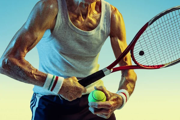 Homem sênior jogando tênis em sportwear no fundo gradiente e luz de néon — Fotografia de Stock