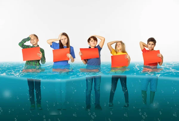 Grupo de crianças com bandeiras vermelhas em branco em pé na água da geleira de fusão, aquecimento global — Fotografia de Stock