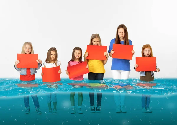 Az olvadó gleccser és a globális felmelegedés vizében álló üres vörös zászlókkal rendelkező gyermekek csoportja — Stock Fotó