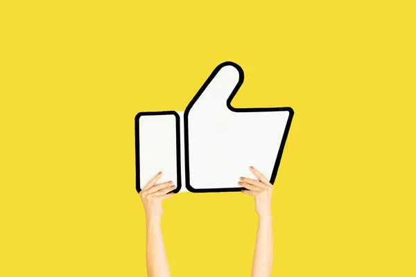Hands holding the sign of like on yellow studio background — Stock Photo, Image