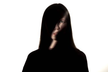 Beyaz stüdyo arka planında karanlıkta bir kızın dramatik portresi..