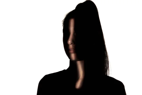 Dramatisches Porträt eines Mädchens im Dunkeln auf weißem Studiohintergrund. — Stockfoto