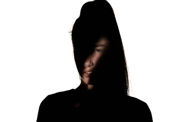 Dramatiskt porträtt av en flicka i mörkret på vit studio bakgrund. — Stockfoto