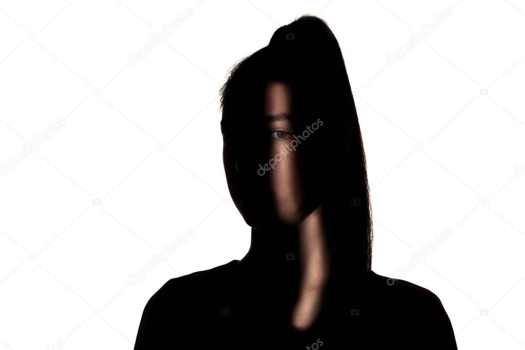 Dramatic portrait of a girl in the dark on white studio background.
