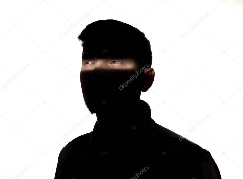 Dramatic portrait of a man in the dark on white studio background.