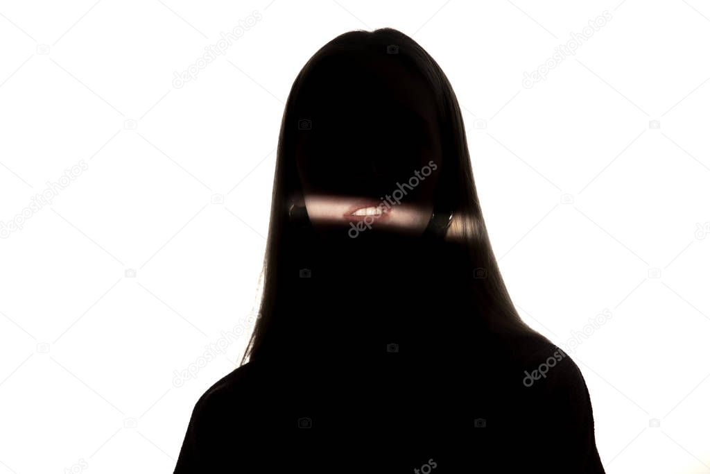 Dramatic portrait of a girl in the dark on white studio background.