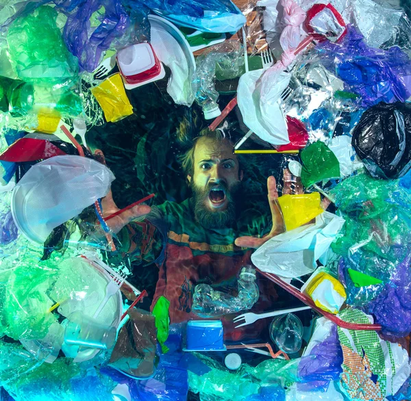 Человек тонет в океанической воде под кучей пластиковых реципиентов, концепция окружающей среды — стоковое фото