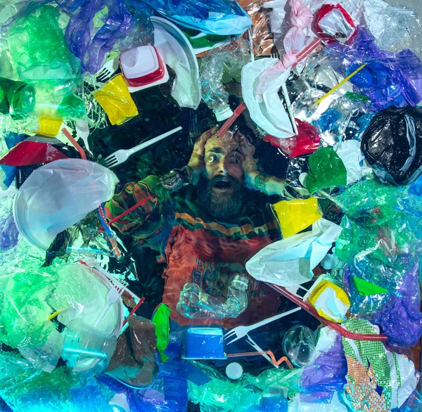 L'uomo che annega nell'acqua dell'oceano sotto plastica recipienti mucchio, concetto di ambiente — Foto Stock