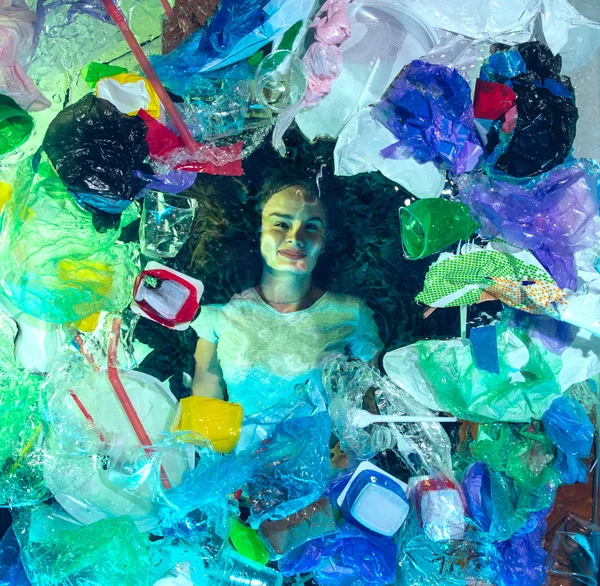 Donna che annega nell'acqua dell'oceano sotto plastica recipienti mucchio, concetto di ambiente — Foto Stock