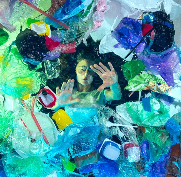 Женщина тонет в океанской воде под кучей пластиковых реципиентов, концепция окружающей среды — стоковое фото
