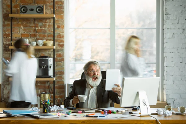 Nervous and tired boss at his workplace busy while people moving near blurred — Stock Photo, Image
