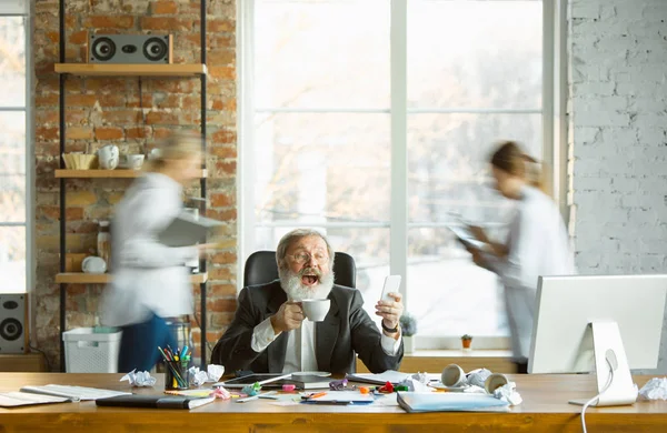 Jefe cansado descansando en su lugar de trabajo mientras la gente se mueve cerca borrosa — Foto de Stock