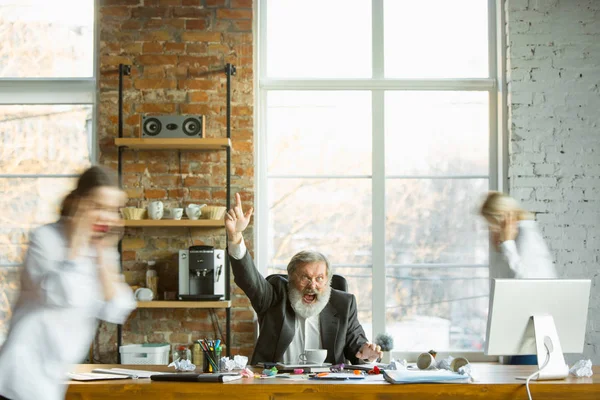 Jefe cansado descansando en su lugar de trabajo mientras la gente se mueve cerca borrosa — Foto de Stock