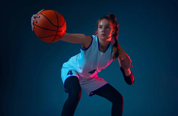 Young caucasian female basketball player on blue studio background in neon light — Stock Photo, Image