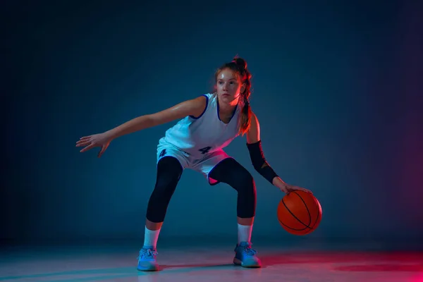 Giovane giocatore di basket femminile caucasico su sfondo blu studio in luce al neon — Foto Stock