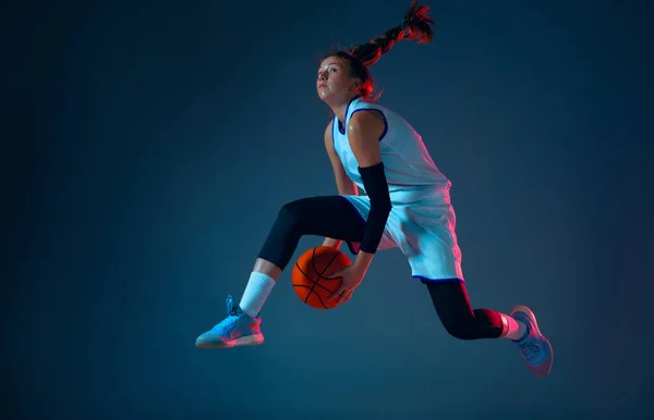 Joven jugador de baloncesto femenino caucásico en fondo estudio azul en luz de neón — Foto de Stock