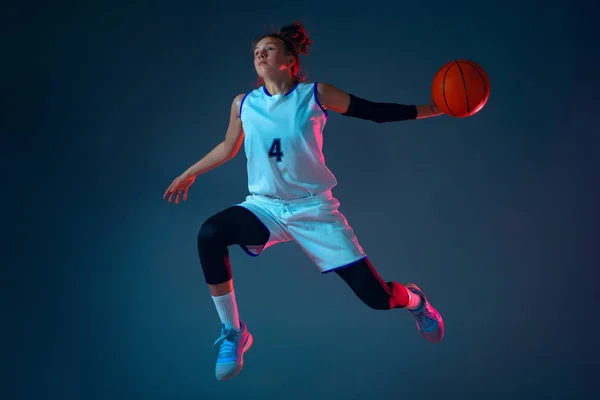 Giovane giocatore di basket femminile caucasico su sfondo blu studio in luce al neon — Foto Stock