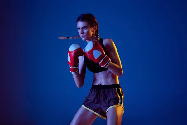 Подходит кавказка в спортивном боксе на синем студийном фоне в неоновом свете — стоковое фото