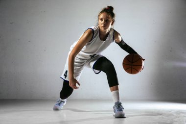 Beyaz duvar arkasında genç beyaz kadın basketbolcu