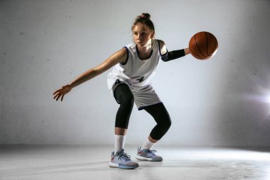 Beyaz duvar arkasında genç beyaz kadın basketbolcu
