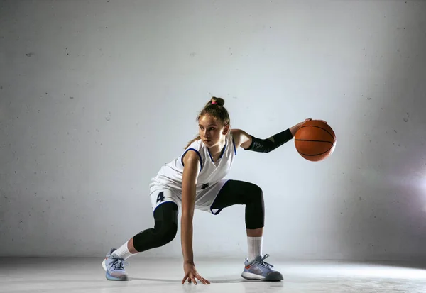 Young caucasian female basketball player against white wall background