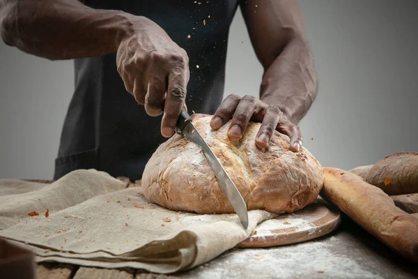 Close up de homem afro-americano fatias de pão fresco com uma faca de cozinha — Fotografia de Stock