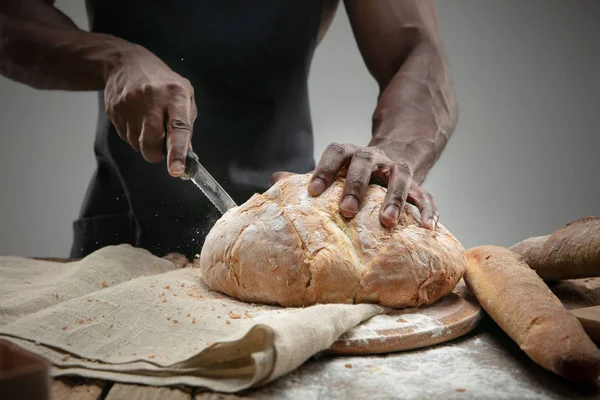 Close up de homem afro-americano fatias de pão fresco com uma faca de cozinha — Fotografia de Stock
