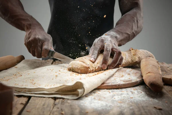 Close up de homem afro-americano fatias de pão fresco com uma faca de cozinha — Fotografia de Stock