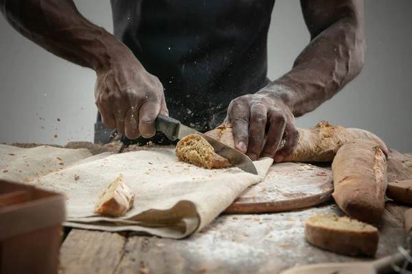 Close up de homem afro-americano fatias de pão fresco com uma faca de cozinha — Fotografia de Stock