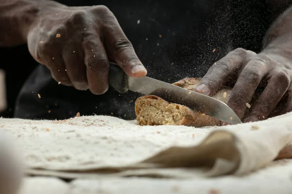 Close up de homem afro-americano fatias de pão fresco com uma faca de cozinha — Fotografia de Stock