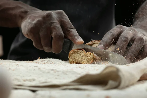 Close up de homem afro-americano fatias de pão fresco com uma faca de cozinha — Fotografia de Stock