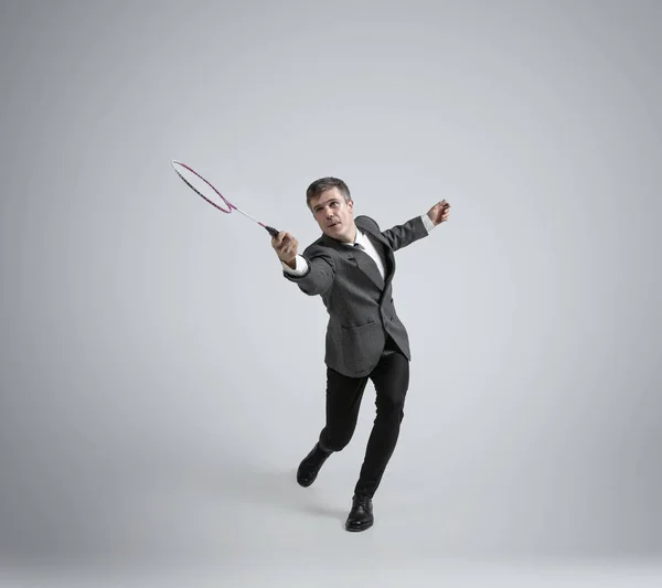 Caucásico hombre en oficina ropa juega bádminton aislado en gris estudio fondo — Foto de Stock