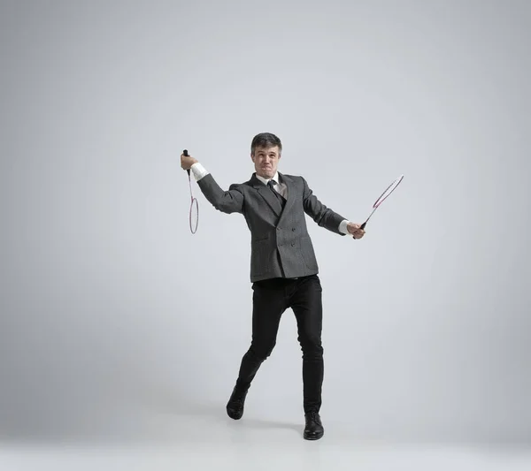 Кавказька людина в офісному одязі грає бадмінтон ізольований на сірому фоні студії — стокове фото