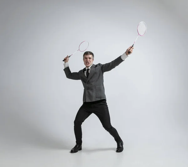 Caucasian man in office clothes plays badminton isolated on grey studio background — Stock Photo, Image