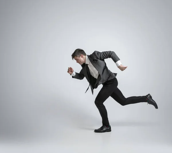 Caucasian man in office clothes running isolated on grey studio background — Stock Photo, Image