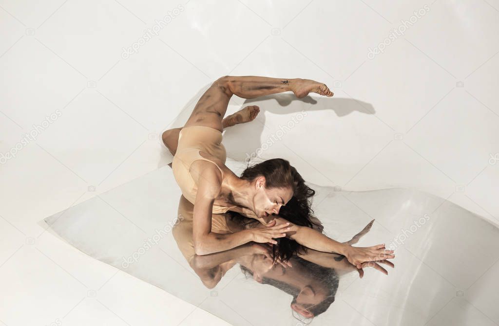 Young and stylish modern ballet dancer on white background with mirrors
